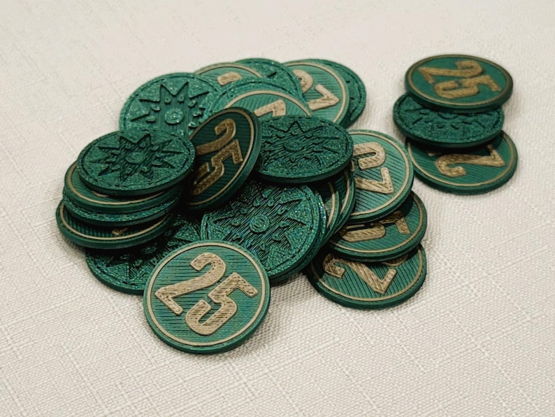A pile of metallic green, circular game coins worth twenty five coins. The coins have a raised "25" on the front and a submerged symbol on the back. These premium board game coins replace the standard card board coins.