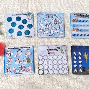 May include: Six square Christmas-themed savings challenge cards with various designs including scratch-off circles, stockings to colour, and star icons. A teal letter K and a red letter B are positioned to the left of the cards.