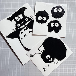 以下が含まれることがあります： アニメ映画「となりのトトロ」のキャラクターをあしらった白黒ステッカーのコレクション。トトロ、ススワタリ、腕と足のある遊び心のあるキャラクターが含まれています。ラップトップ、ノート、その他のアイテムの装飾に最適です。