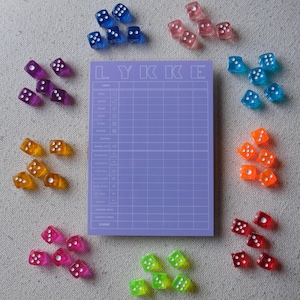 Könnte beinhalten: Ein rechteckiger violetter Punkteblock mit dem Wort LYKKE am oberen Rand, umgeben von Gruppen durchsichtiger sechsseitiger Würfel in verschiedenen Farben wie Blau, Pink, Lila, Orange, Rot und Grün, alle mit weißen Augen.