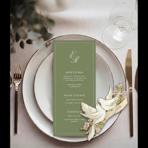 May include: A formal table setting with a green menu card, white plates, and gold silverware. The menu card features the initials "ER" and a list of courses. A decorative dove and floral accent adds a touch of elegance.