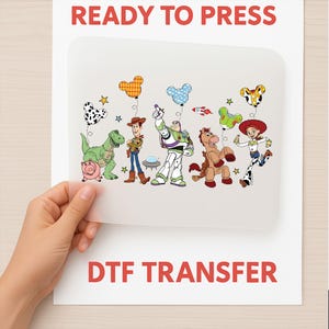 Op de afbeelding: Een DTF-transfervel met cartoonfiguren van Toy Story. Het vel toont Woody, Buzz Lightyear, Jessie, Rex en andere personages, met de rode tekst "READY TO PRESS" en "DTF TRANSFER".