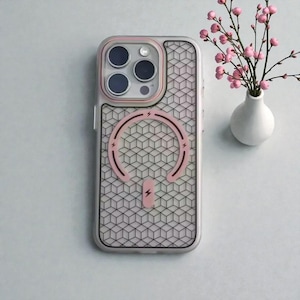 Könnte beinhalten: Transparente Handyhülle mit geometrischem Muster und rosa Akzenten. Die Hülle hat einen rosa Ladekreis und eine rosa Kameraumrandung. Eine kleine weiße Vase mit rosa Blumen befindet sich im Hintergrund.