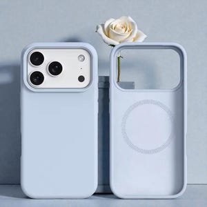 Op de afbeelding: Twee lichtblauwe telefoonhoesjes, één met camera-uitsparingen en de andere met een cirkelvormig ontwerp, worden getoond. Een witte roos is tussen de hoesjes geplaatst. De hoesjes zijn gemaakt van een glad materiaal en beschermen een telefoon.