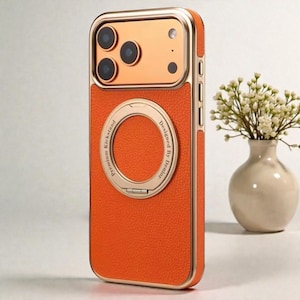 Puede incluir: Funda de teléfono naranja y dorada con un acabado texturizado. La funda presenta un soporte de anillo dorado y el texto "Premium Kickstand Designed By Denior". El marco de la cámara es dorado.
