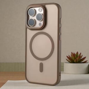 Può includere: Custodia trasparente per telefono con bordo marrone e design a cerchio magnetico marrone. La custodia ha un ritaglio per la fotocamera con un anello in metallo marrone. La custodia è progettata per proteggere il telefono.