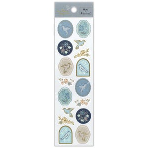 May include: A sheet of decorative stickers featuring various designs of birds, flowers, and floral patterns in shades of blue, beige, and gold. The stickers are in different shapes, including circles, ovals, and arched frames. The brand name "Nuku" is printed at the top.