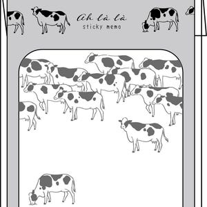 Peut inclure: Un bloc-notes adhésif gris avec une illustration de vache en noir et blanc. Le texte "Ah là là sticky memo" est imprimé en haut. Le bloc-notes présente une bordure et des dessins de vaches.