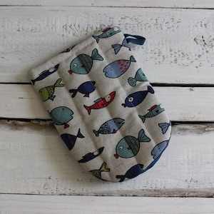 Könnte beinhalten: Ein gesteppter Ofenhandschuh mit einem verspielten Fischmuster. Der Handschuh hat einen hellgrauen Hintergrund mit bunten Fischillustrationen in Blau-, Rot- und Grüntönen. Eine dunkelblaue Schlaufe ist zum Aufhängen angebracht.