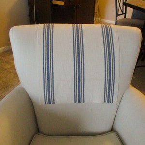 May include: A white armchair with a blue and white striped cushion on the back.