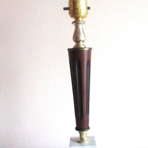 May include: A vintage table lamp with a brown wooden base and a white marble base. The lamp has a gold metal socket and a silver metal finial.