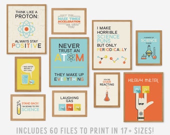 May include: A collection of ten framed science-themed wall art prints featuring colorful graphics and humorous puns about protons, atoms, and chemistry. The prints include text such as Think Like a Proton, Never Trust an Atom, and Heavy Metal, displayed in light wood frames.