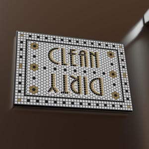 May include: A rectangular refrigerator magnet with the words "CLEAN" and "DIRTY" in gold lettering. The magnet has a mosaic tile design with black, white, and gold accents. Several white square magnets are also visible on the refrigerator door.