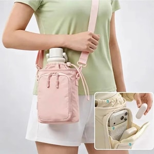 May include: A light pink water bottle carrier bag with an adjustable shoulder strap and a front zippered pocket. The bag features a cylindrical compartment for a bottle and a secondary pocket containing a smartphone and a small white rectangular object.