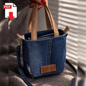 May include: A small, blue denim tote bag with brown handles and a detachable shoulder strap. The bag features a brown leather patch with the text "Hello meche jeans". The bag has a zipper closure and a distressed look.