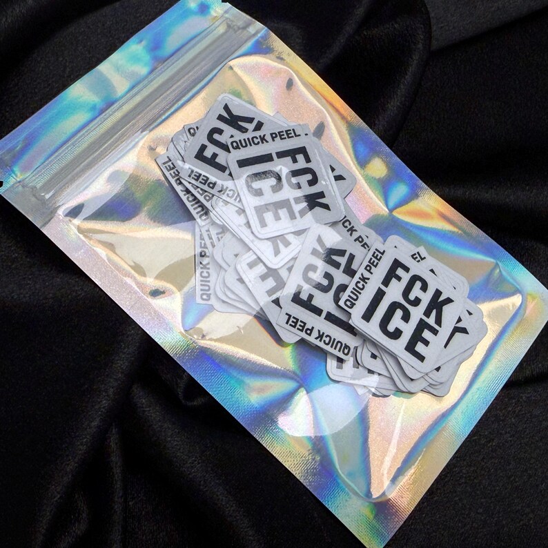 K&ouml;nnte beinhalten: Eine transparente, irisierende Plastikt&uuml;te mit mehreren wei&szlig;en Aufklebern. Jeder Aufkleber tr&auml;gt den Text "FCK ICE QUICK PEEL" in schwarzer, fetter Schrift. Die T&uuml;te ist versiegelt und liegt auf einer schwarzen Oberfl&auml;che.
