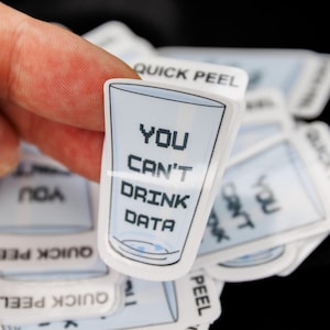 May include: A die-cut sticker shaped like a glass, featuring a light blue tint and the black pixelated text "YOU CAN'T DRINK DATA" printed on the front. The sticker includes a white tab at the top with the black text "QUICK PEEL".