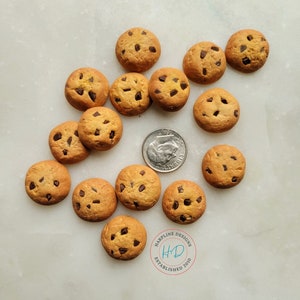 May include: A collection of miniature chocolate chip cookies, each with a golden-brown hue and dark chocolate chips. A U.S. dime is included for size reference. The cookies are arranged on a light-colored surface. The image includes a logo that says "HARPLINE DESIGNS ESTABLISHED 2010".