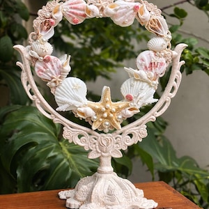 May include: A white ceramic mug with a black handle and the text "But First, Coffee" in a handwritten style. The mug is on a white surface. The mug is 10 cm tall.