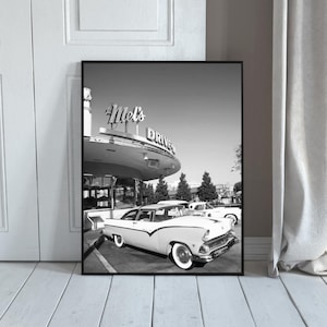 May include: Black and white framed print featuring a classic diner scene. A vintage car is parked in front of Mel's Drive-In, with the diner's sign visible. The image evokes a retro, nostalgic feel.