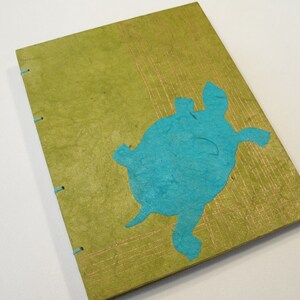Pu&ograve; includere: Un diario artigianale verde con un ritaglio di carta turchese di una tartaruga sulla copertina.