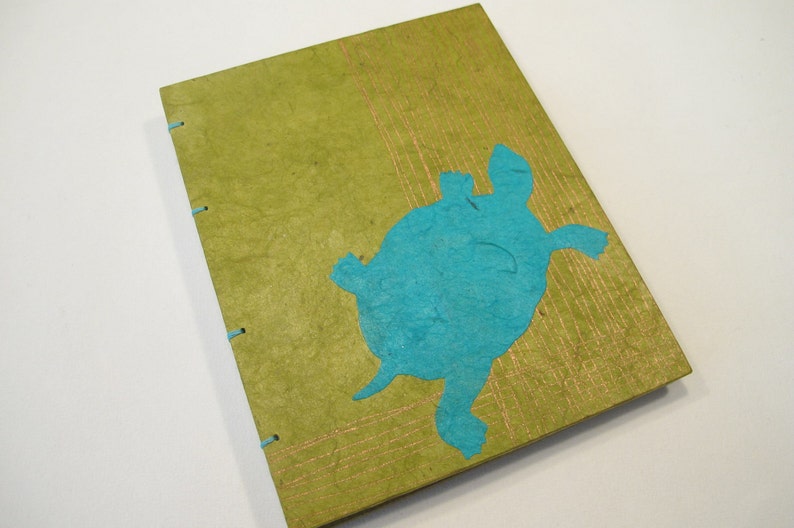 Pu&ograve; includere: Un diario artigianale verde con un ritaglio di carta turchese di una tartaruga sulla copertina.
