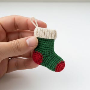 Peut inclure: Une petite chaussette de Noël crochetée, verte avec des détails rouges au talon et à la pointe. Le bord supérieur est crème et une boucle est attachée pour suspendre l'ornement. Décoration de Noël faite à la main.