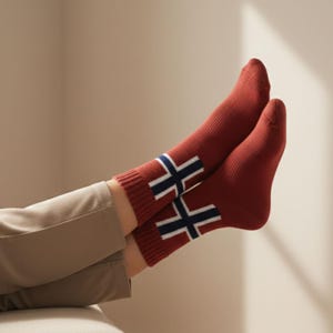 Puede incluir: Calcetines rojos con un diseño de cruz blanca y azul marino. Los calcetines son de punto y visibles desde los tobillos hacia abajo. Estilo cálido y cómodo.