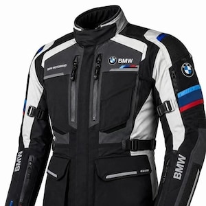 Può includere: Una giacca da moto nera, grigia e bianca con il logo BMW Motorrad sul petto e sulle maniche. La giacca presenta diverse tasche con cerniera, cinghie laterali regolabili e strisce decorative blu e rosse sulle braccia e sul petto.
