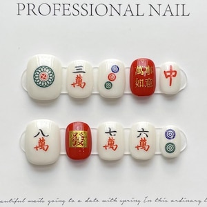 May include: White press-on nails with red and green Chinese characters and symbols. Some nails are red, others white. The text "PROFESSIONAL NAIL" is at the top. The nails are arranged in two rows of five.