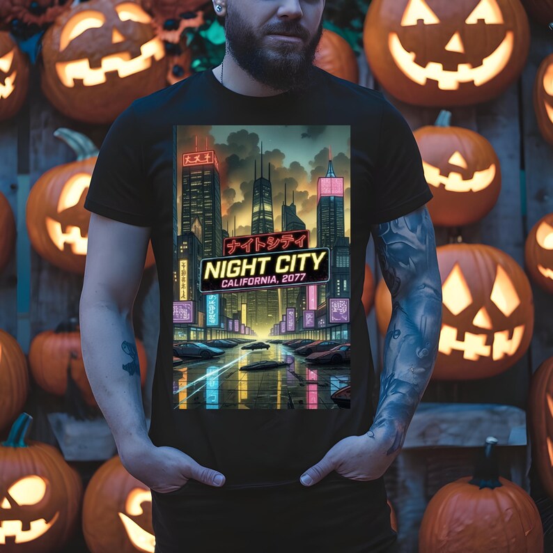 Op de afbeelding: Zwart t-shirt met een levendige afbeelding van een futuristische stad met neonlichten. Het ontwerp bevat de tekst "NIGHT CITY CALIFORNIA, 2077". De achtergrond bestaat uit uitgesneden pompoenen.