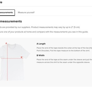 Op de afbeelding: Een wit t-shirt met stippellijnen die meetpunten voor lengte en breedte aangeven. De afbeelding maakt deel uit van een maattabel, met tekst die uitlegt hoe je het shirt moet meten. De maten kunnen tot 5 cm afwijken.