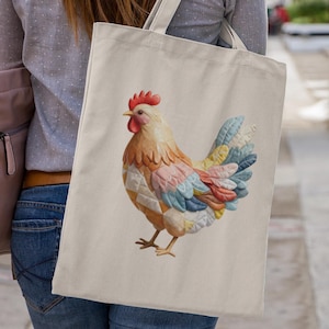 Op de afbeelding: Een crèmekleurige draagtas met een kleurrijke hanenillustratie. De haan heeft een rode kam en lellen, met veren in tinten geel, oranje, roze, blauw en groen. De tas wordt over de schouder gedragen.