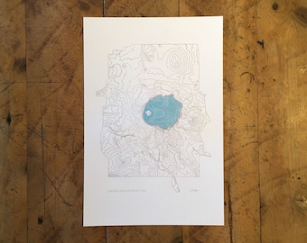 May include: A black and white line drawing of Crater Lake National Park, Oregon, with contour lines showing the elevation of the land. The lake is a light blue color.