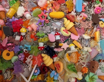 May include: A collection of assorted colorful charms featuring miniature food items like ice cream cones, mushrooms, candy hearts with text like BE MINE and HUG ME, stars, flowers, and mermaid tails, all attached to silver metal lobster clasps.