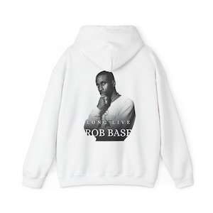 May include: A white hooded sweatshirt featuring a black and white photographic print on the back. The graphic depicts a person with a hand near their chin, accompanied by the text "LONG LIVE ROB BASE" printed in a clean, white serif font.