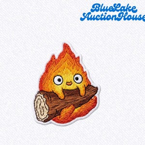 May include: Embroidered patch featuring a cartoon fire character holding a log. The fire is depicted in shades of orange and yellow with a smiling face and large eyes. The text "Blue Lake Auction House" is in blue script.