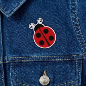 May include: A white ceramic mug with a black handle and the text "But First, Coffee" in a bold, black font. The mug is set against a blurred background, suggesting a cozy setting.