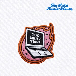 May include: An embroidered patch featuring a laptop with the text TOO MANY TABS on the screen. The laptop is set against a pink background with an orange flame border, small black stars, and lightning bolt accents, all outlined in dark thread.