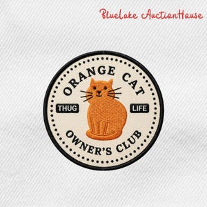 May include: Embroidered patch featuring an orange cat illustration within a circular design. The text "ORANGE CAT OWNER'S CLUB" and "THUG LIFE" are included. The patch has a black border and a cream-colored background.