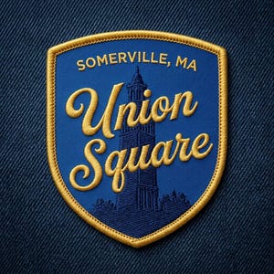 May include: A blue and gold embroidered patch with the text "SOMERVILLE, MA" at the top. The words "Union Square" are in a flowing gold script. A dark blue illustration of a tower is in the center. The patch is shield-shaped.