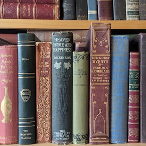 Puede incluir: Una colecci&oacute;n de libros antiguos en una estanter&iacute;a de madera. Los lomos muestran t&iacute;tulos como "Heaven Home and Happiness" y "The Great Events". Los colores var&iacute;an desde rojos y azules intensos hasta verdes y marrones apagados. Los libros var&iacute;an en tama&ntilde;o y encuadernaci&oacute;n.