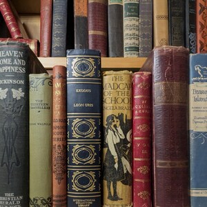 Puede incluir: Una colecci&oacute;n de libros antiguos con varios colores y texturas. Los t&iacute;tulos incluyen "Heaven Home and Happiness", "Exodus" y "Treasure Island". Las espinas muestran elementos decorativos y papel envejecido, creando una est&eacute;tica vintage.