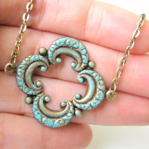 May include: A gold chain necklace with a turquoise blue pendant featuring a decorative, ornate design.