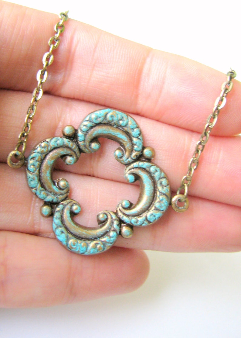 May include: A gold chain necklace with a turquoise blue pendant featuring a decorative, ornate design.