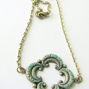 May include: A gold chain necklace with a turquoise and gold pendant featuring a quatrefoil design.