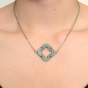 May include: A silver chain necklace with a turquoise blue pendant in the shape of a four-leaf clover.