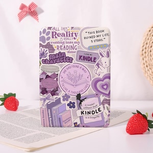 May include: A purple Kindle case covered in stickers with book-themed designs and text. The stickers include phrases like "Main Character," "I love my Kindle," and "A reader without their Kindle is a tragedy."