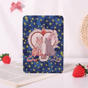 May include: A rectangular card featuring a dark blue background with yellow stars. In the centre, a white heart frame contains two cats: one wearing silver armour with a sword, and the other wearing a pink pointed hat with a ruffled collar.