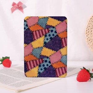 May include: A rectangular patchwork design in shades of pink, orange, yellow, blue, and purple. The design features various patterns, including polka dots, stripes, and swirls, stitched together with white thread. The item is standing upright on a white surface.